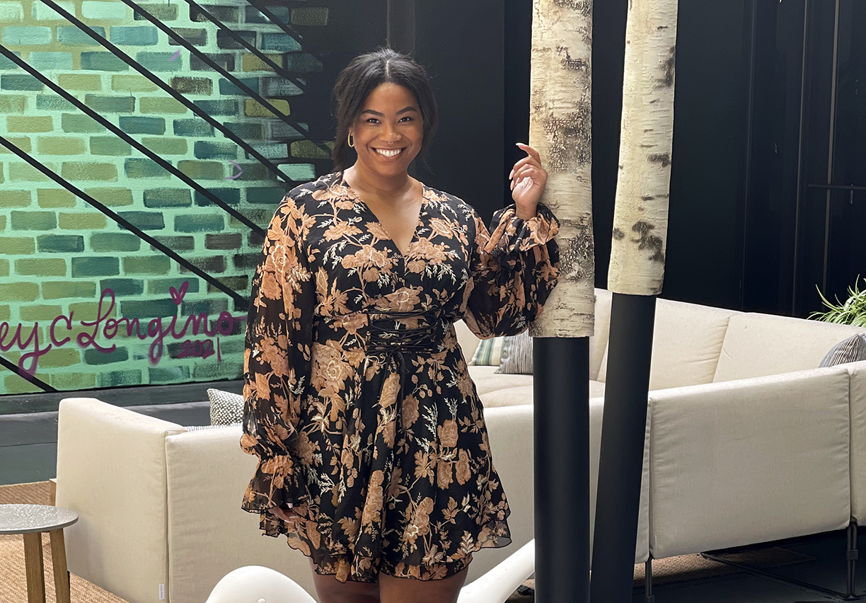 Photo of Amber Hagans posing in a floral dress in a lounge.