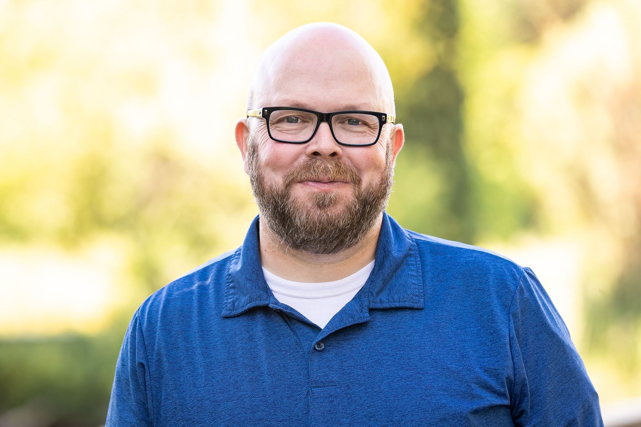 Headshot of Ben Melton posing in a blue shirt.