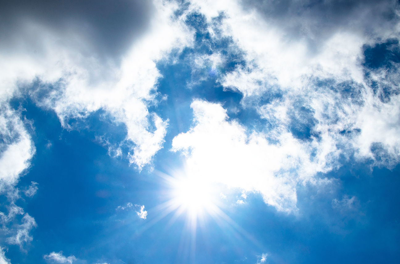 Blue sky with overcast clouds and sun peeking out.