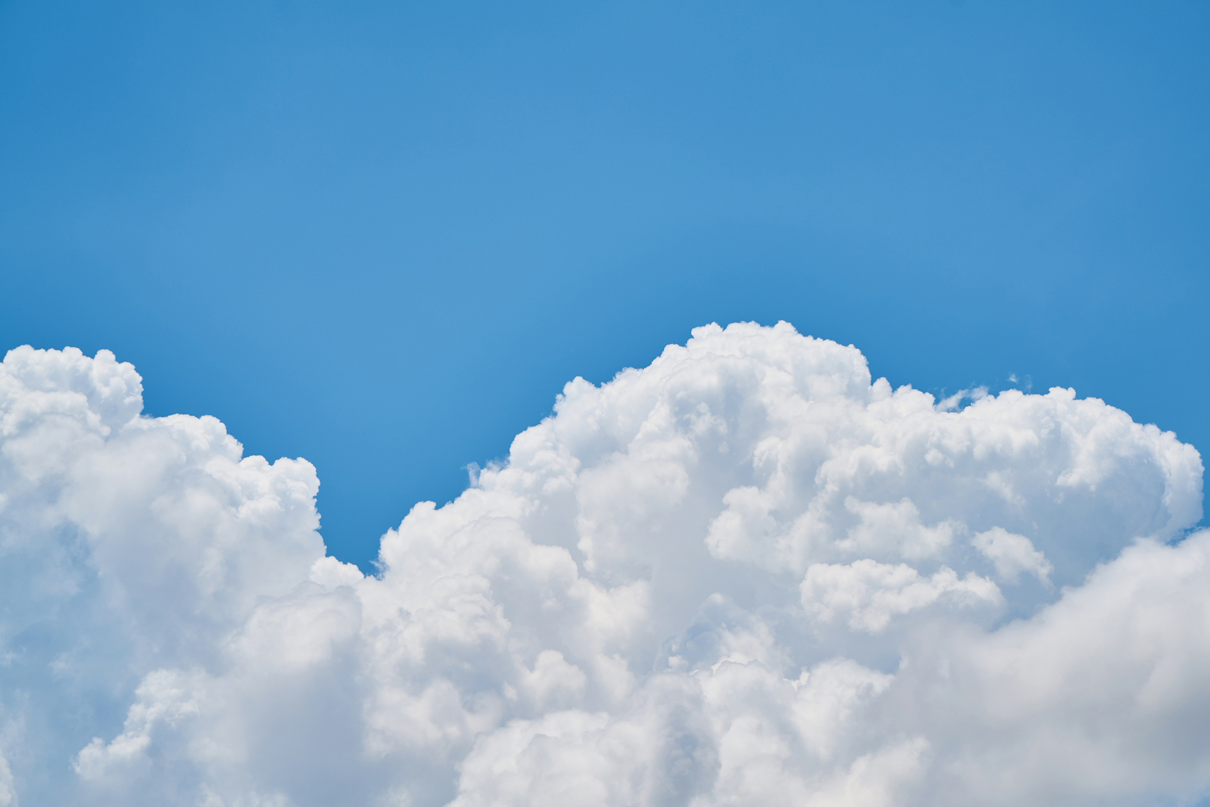 Clear blue sky with white clouds filling half of the sky.