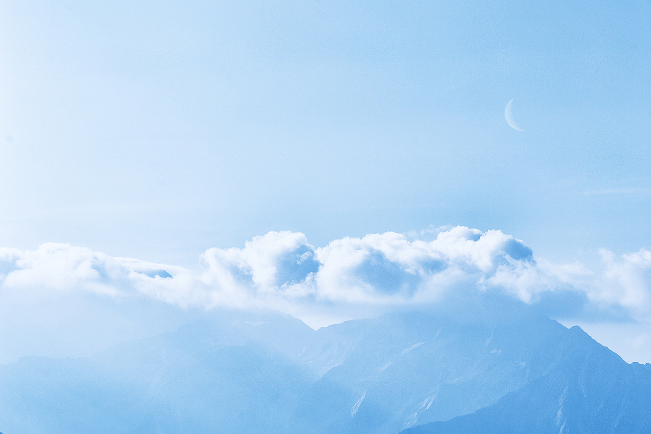 Pale blue sky with clouds and a quarter moon showing in the distance.