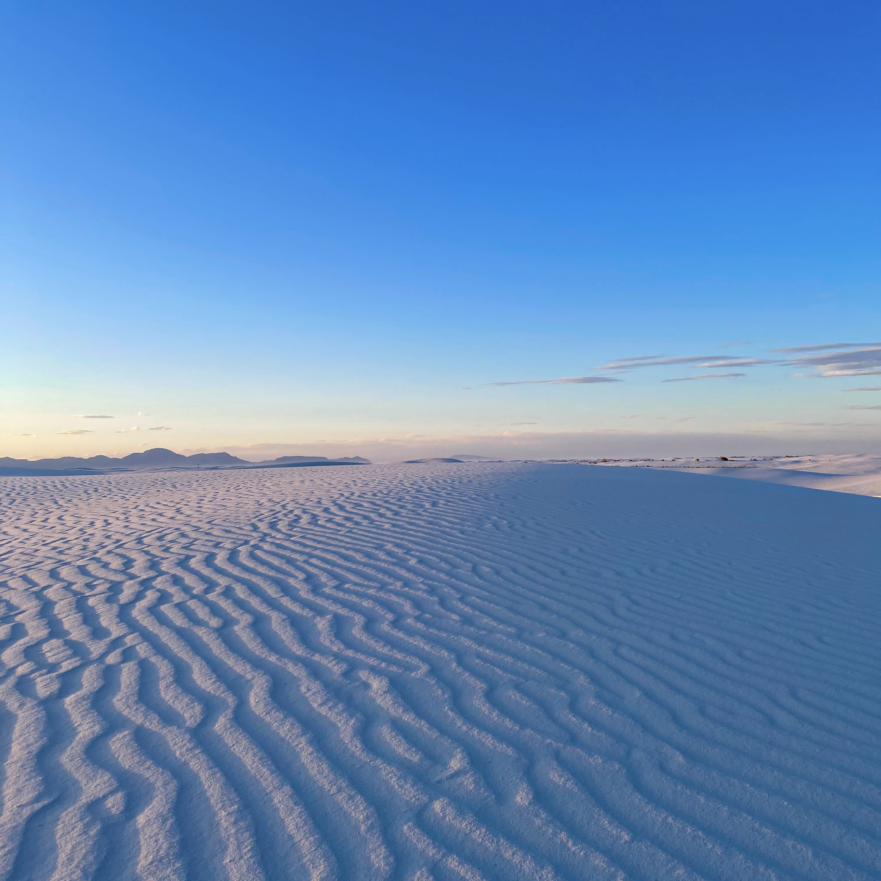 Mostly clear blue sky overlooking sandy beach.