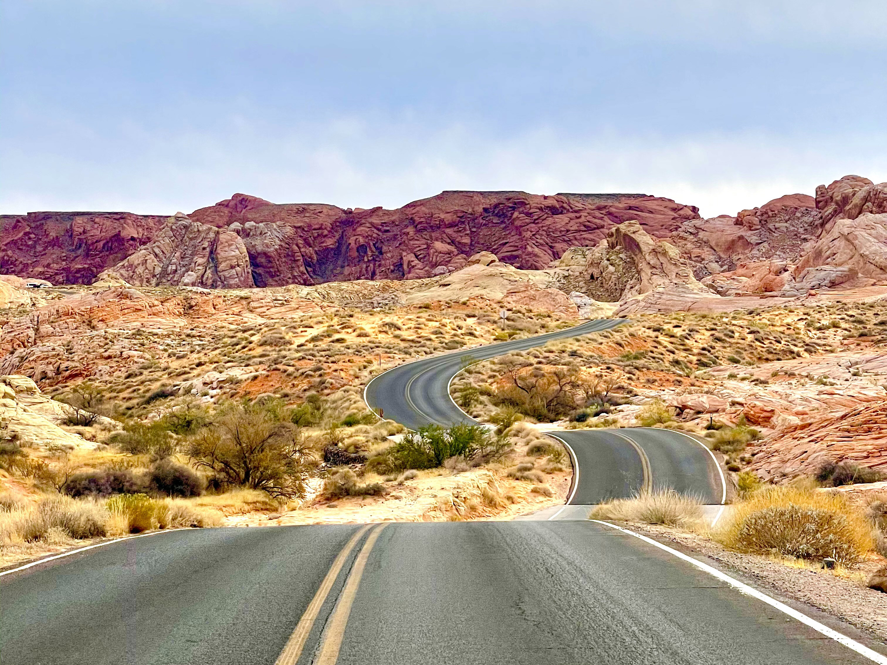 Winding road going through desert and canyons in the distance.