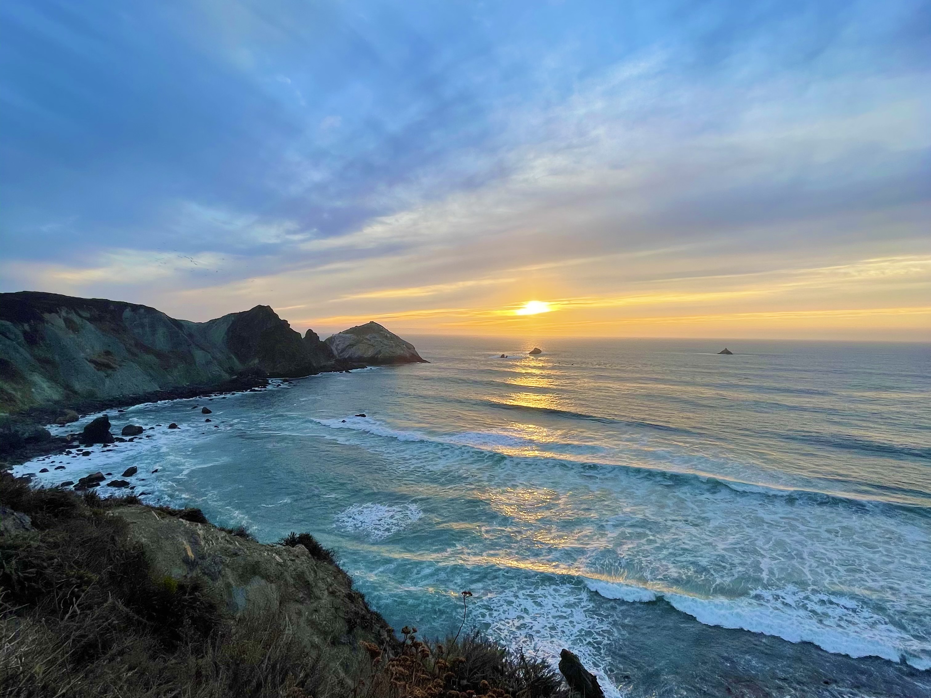 Ocean at a cove with the sunset in the background.