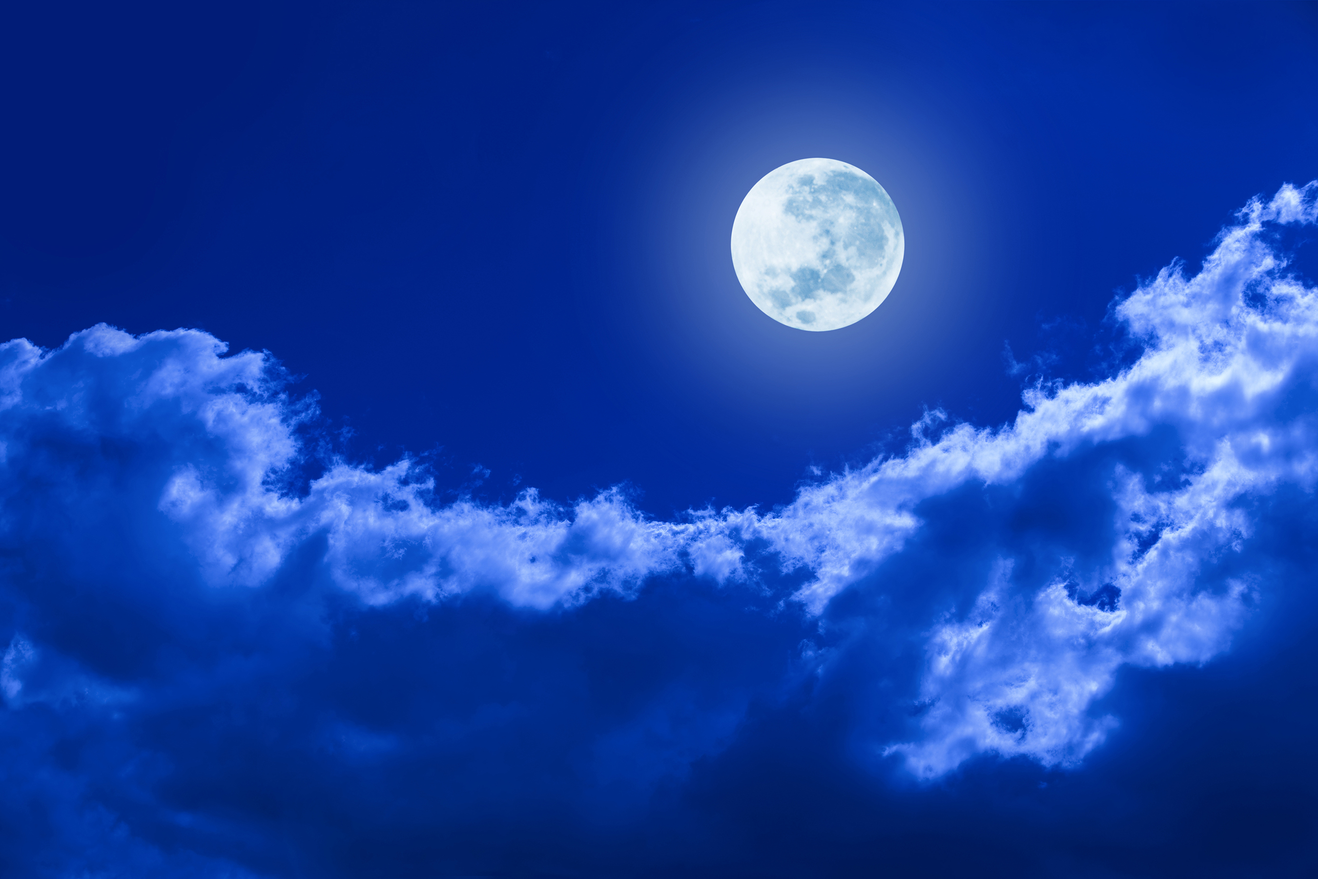 A blue night sky with light blue clouds and a full moon.
