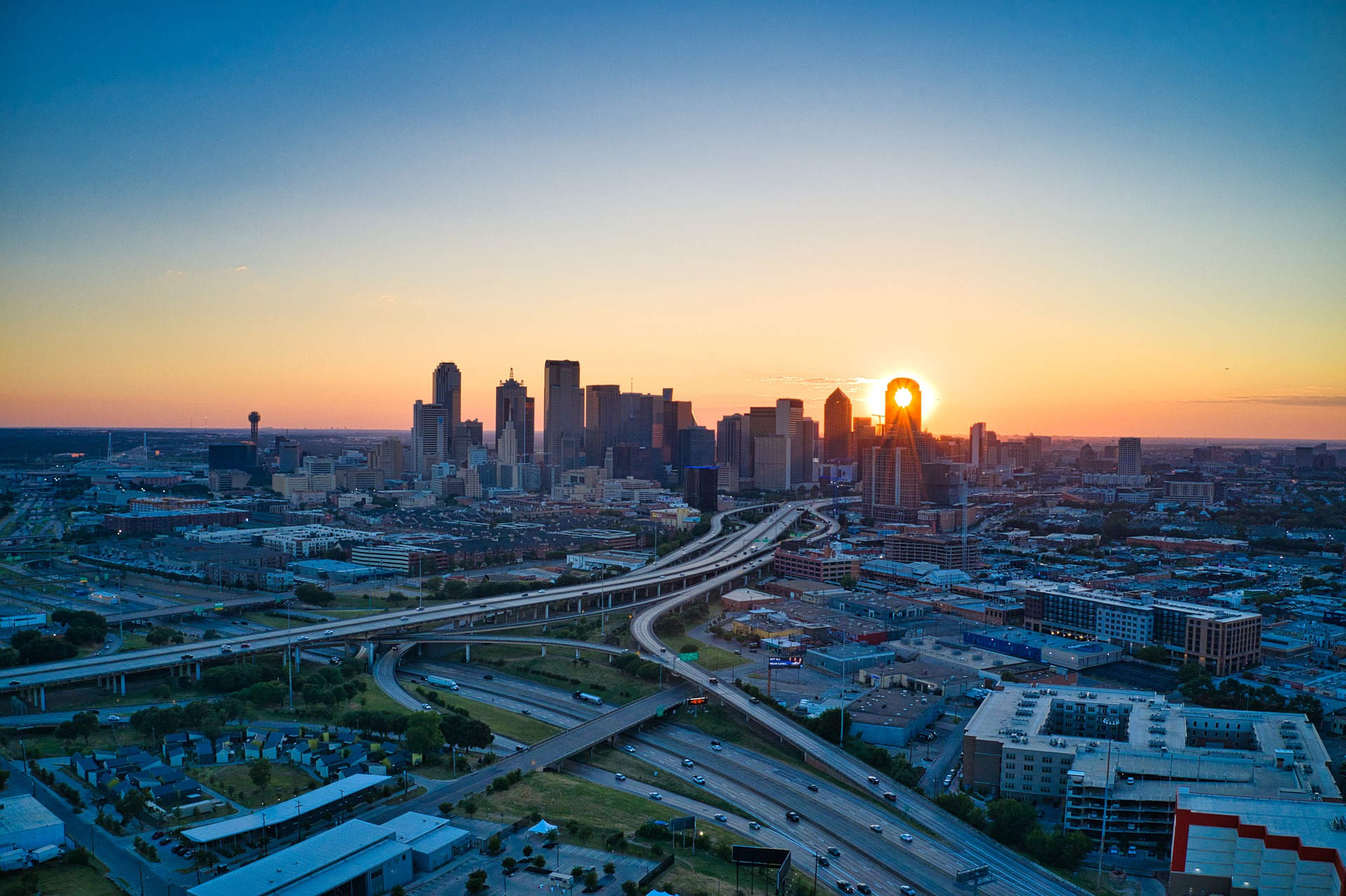 Cityscape with roads and a sunset in the background.