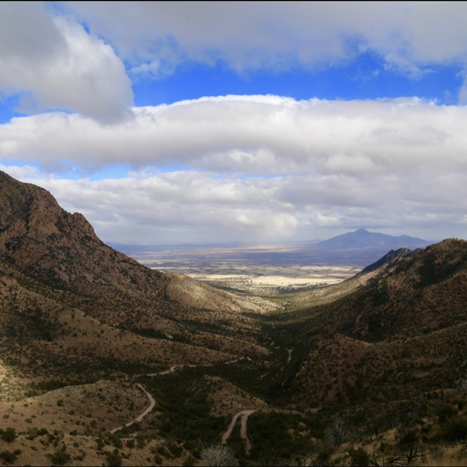 Cloudy sky overlooking mountain valley.
